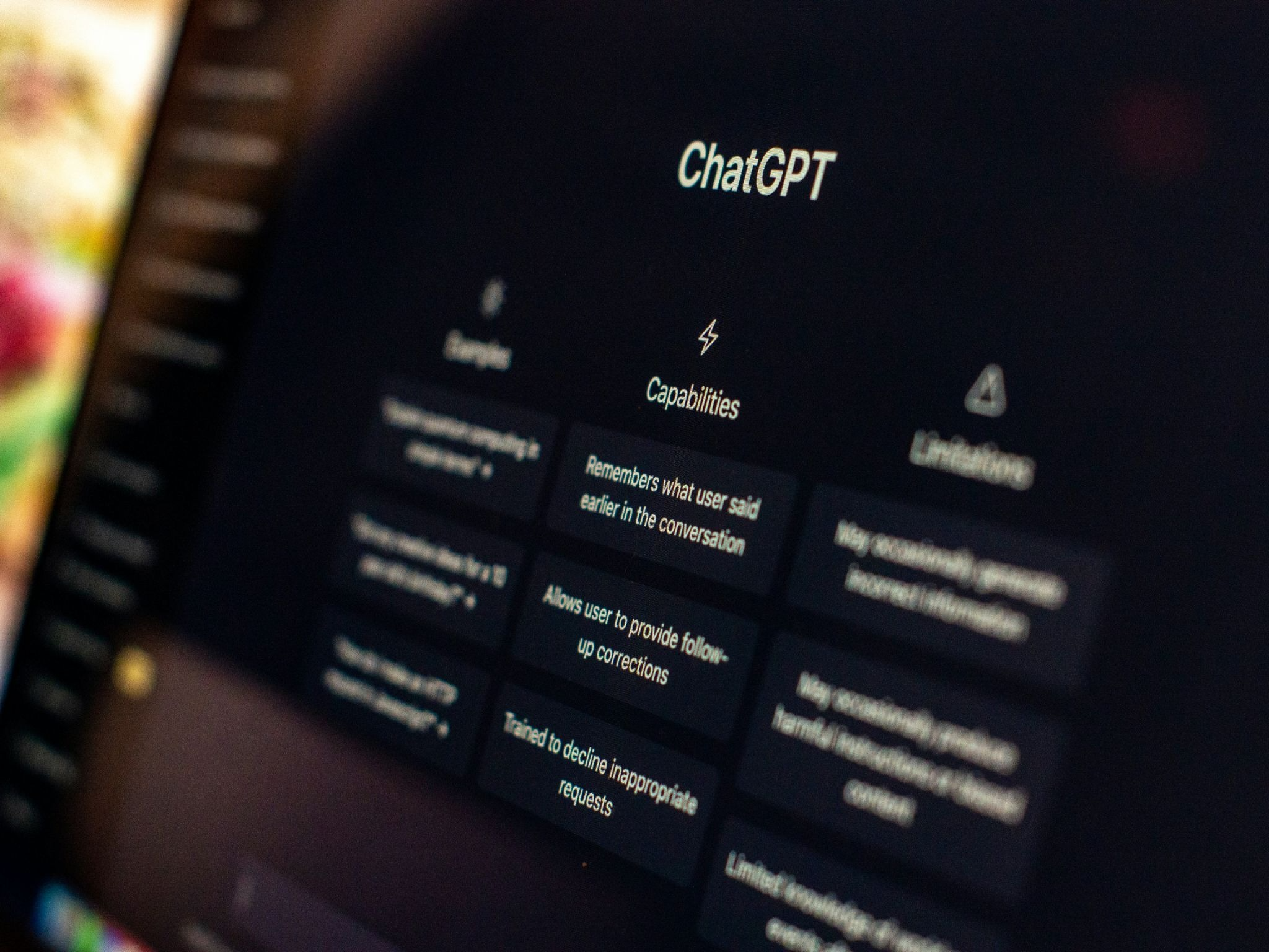 Close-up of a laptop screen displaying the ChatGPT interface, showing the Capabilities section with features like conversation memory and follow-up corrections.
